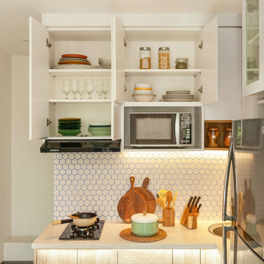 A stylish kitchen showcasing open cabinets with dishes, cookware, and modern appliances.